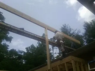 Carpenter setting a ridge beam over a new addition frame — Ice Dam Removal by Roofing Brothers in Many