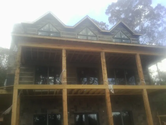 Dormers and porch framing on a large log home under construction — Roof Coating work by our crew in Many