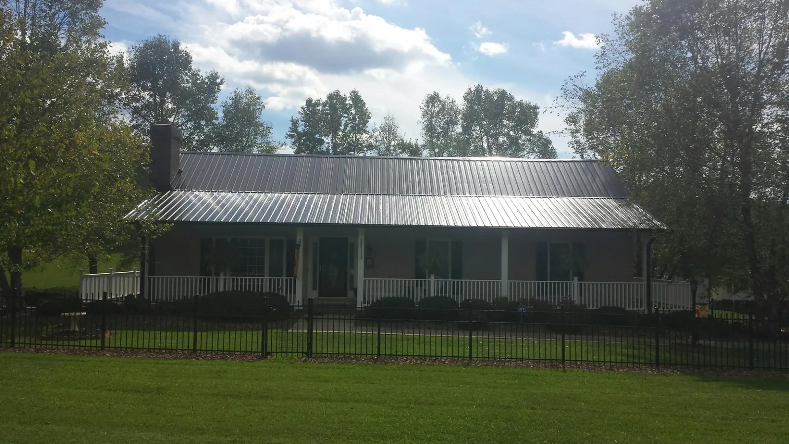 Gray metal roof on a brick ranch with a full width front porch — Gutter Guard Installation work by our crew in Many