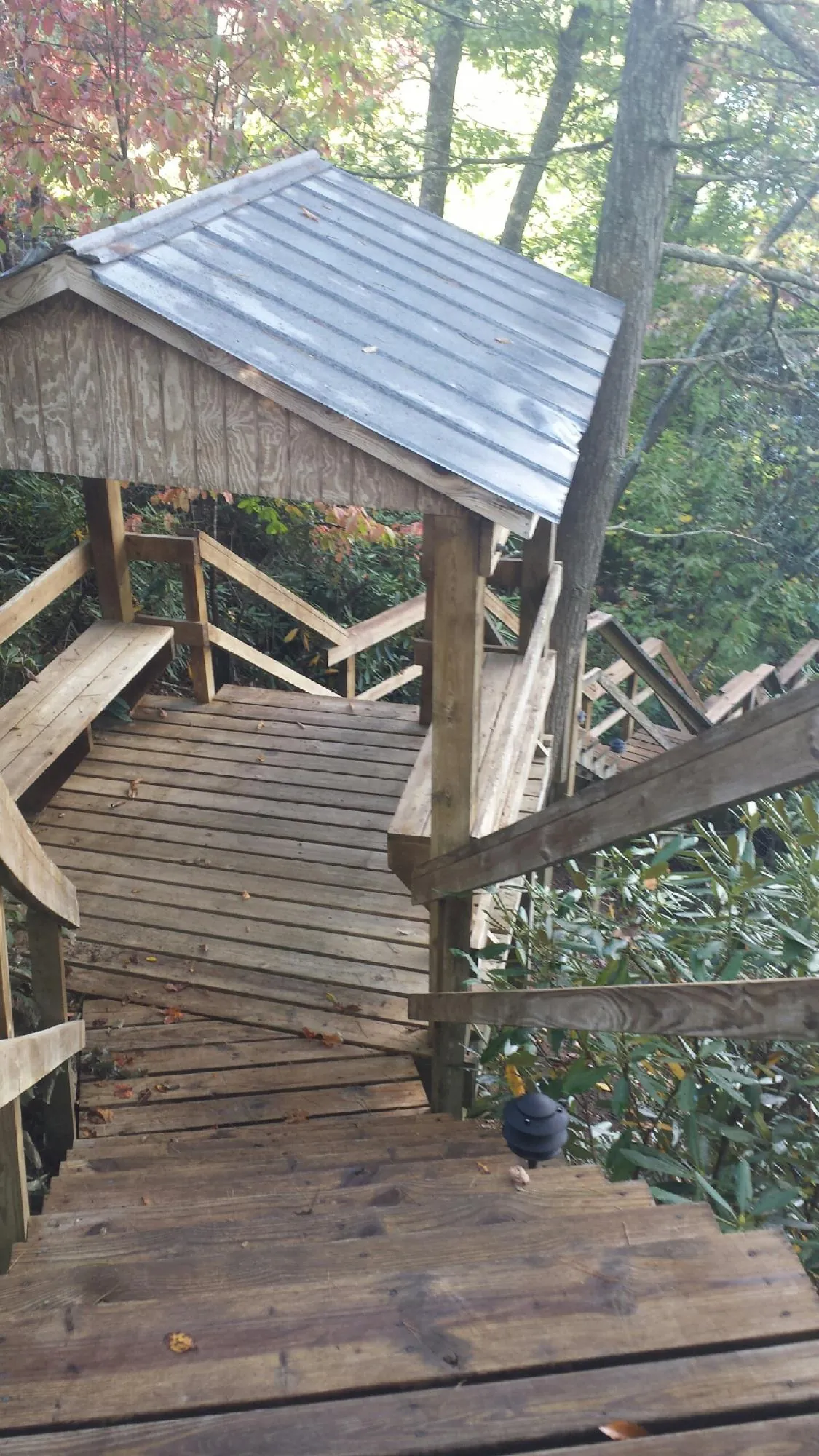 Metal roofed shelter over wooden steps on a wooded walkway — Skylight Repair & Installation work by our crew in Many