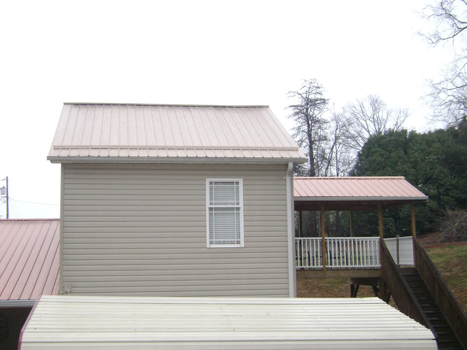 Tan metal roofs on a two story addition and attached porch, from a Roof Replacement job in Many