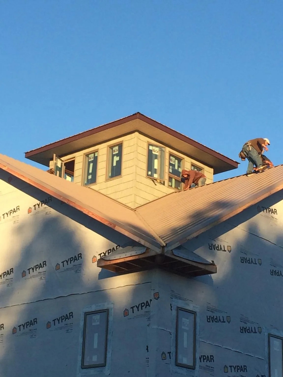 Roofers working around a rooftop cupola on a new metal roof at sunset — Roof Waterproofing in Many by Roofing Brothers